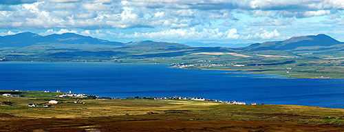 Picture of a view from a hill over a sea loch with two villages on the shore